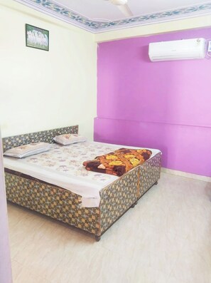 A single bed with patterned bedding, a wall-mounted air conditioner, and a patterned headboard. - Hotel Mostel Guest House - Jaipur (Jaipur)