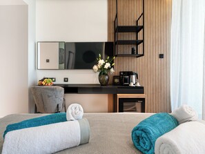 Habitación de hotel moderna con sofá, estación de café, espejo y vistas de la ciudad.