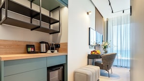 Een moderne keuken met inbouwapparatuur, een eethoek met een tafel en stoelen, en een groot raam met gordijnen.