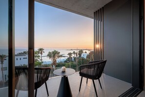 Un balcon avec deux chaises, une table et une vue sur la mer et les bâtiments.