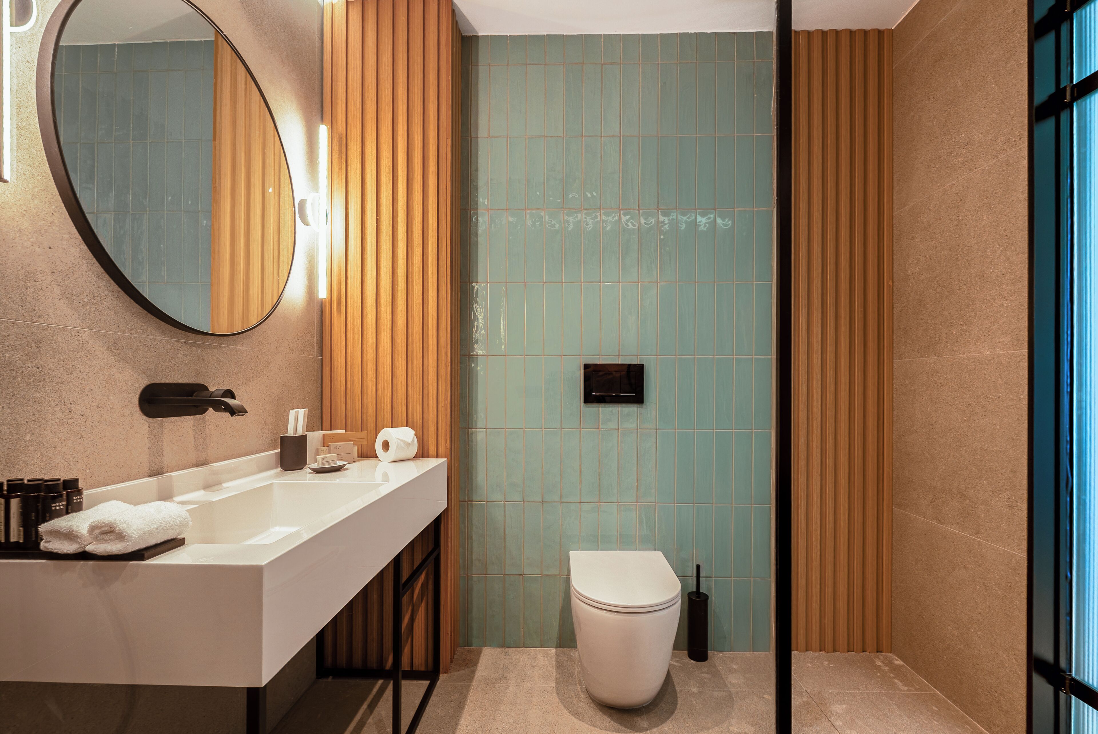 A modern bathroom with a white sink, mirror, and toilet.