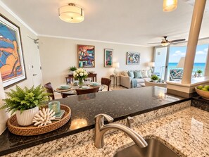 A modern kitchen with granite countertops, a stainless steel sink, and a dining area with a table set for two. - Beachfront * Washer/D * Walk 2 eat (Carolina)