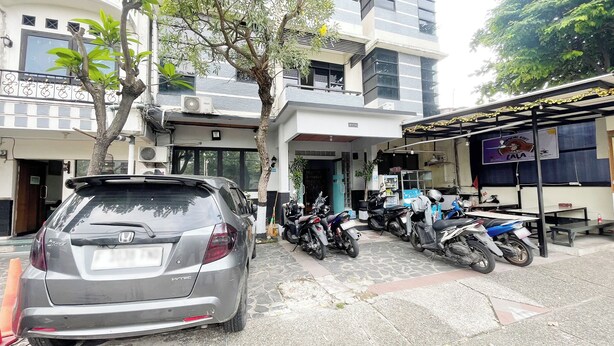 Un espace de stationnement où se trouvent une voiture Honda et plusieurs motos.