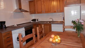 Eine kleine Küche mit Holzausstattung, einer Mikrowelle, einem Spülbecken, einer Waschmaschine und einem Esstisch mit Obst.