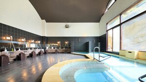 Un espace piscine intérieur moderne, doté d’un design incurvé, d’un coin salon avec des chaises et d’un comptoir proposant divers services.