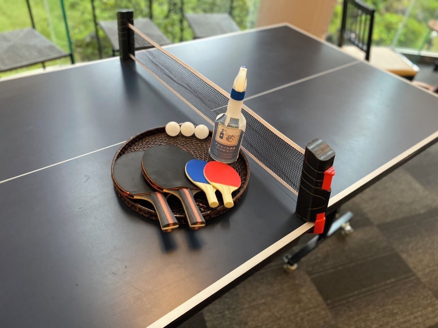 Een tafeltennistafel met twee batjes, een fles en drie ballen.