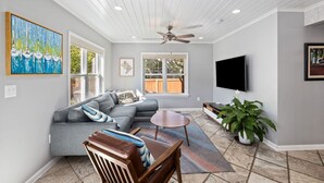 A modern living room with a gray sectional sofa, a wooden coffee table, and a TV mounted on the wall. - Clarendon Getaway, 6-BR Luxurious Urban Estate (Arlington)