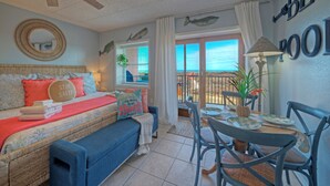 Un dormitorio con cama, ventana con vistas, ventilador de techo y zona de comedor con sillas y mesa.