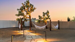 A desert landscape with a stone pathway leading to a hammock and a tree. - Bocce, Pool+Spa, Game Room, Firepit | Modern Oasis | Yucca Haven by AvantStay (Yucca Valley)