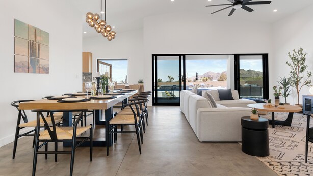 A spacious living area with a dining table, chairs, a sofa, and a ceiling fan. - Bocce, Pool+Spa, Game Room, Firepit | Modern Oasis | Yucca Haven by AvantStay (Yucca Valley)