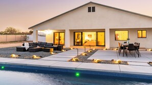 A modern house with a swimming pool, outdoor seating, and a patio area. - Bocce, Pool+Spa, Game Room, Firepit | Modern Oasis | Yucca Haven by AvantStay (Yucca Valley)