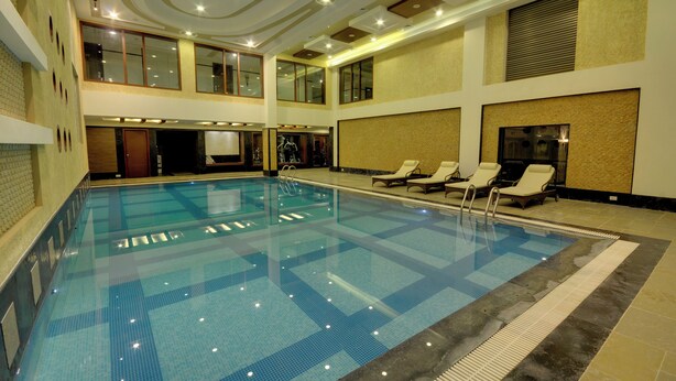 Ein großer, überdachter Pool mit Liegestühlen und einer hohen Decke mit eingelassener Beleuchtung.