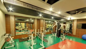 Ein Fitnessstudio mit Trainingsgeräten, Spiegeln und einem Fernseher.