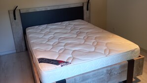 Een bed met houten frame en een matras met etiket.