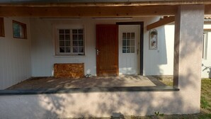 Een huis met veranda, een houten deur en een raam.