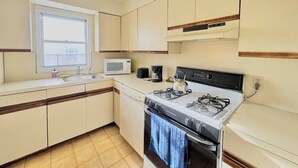A compact kitchen with a gas stove, microwave, and a window above the sink.