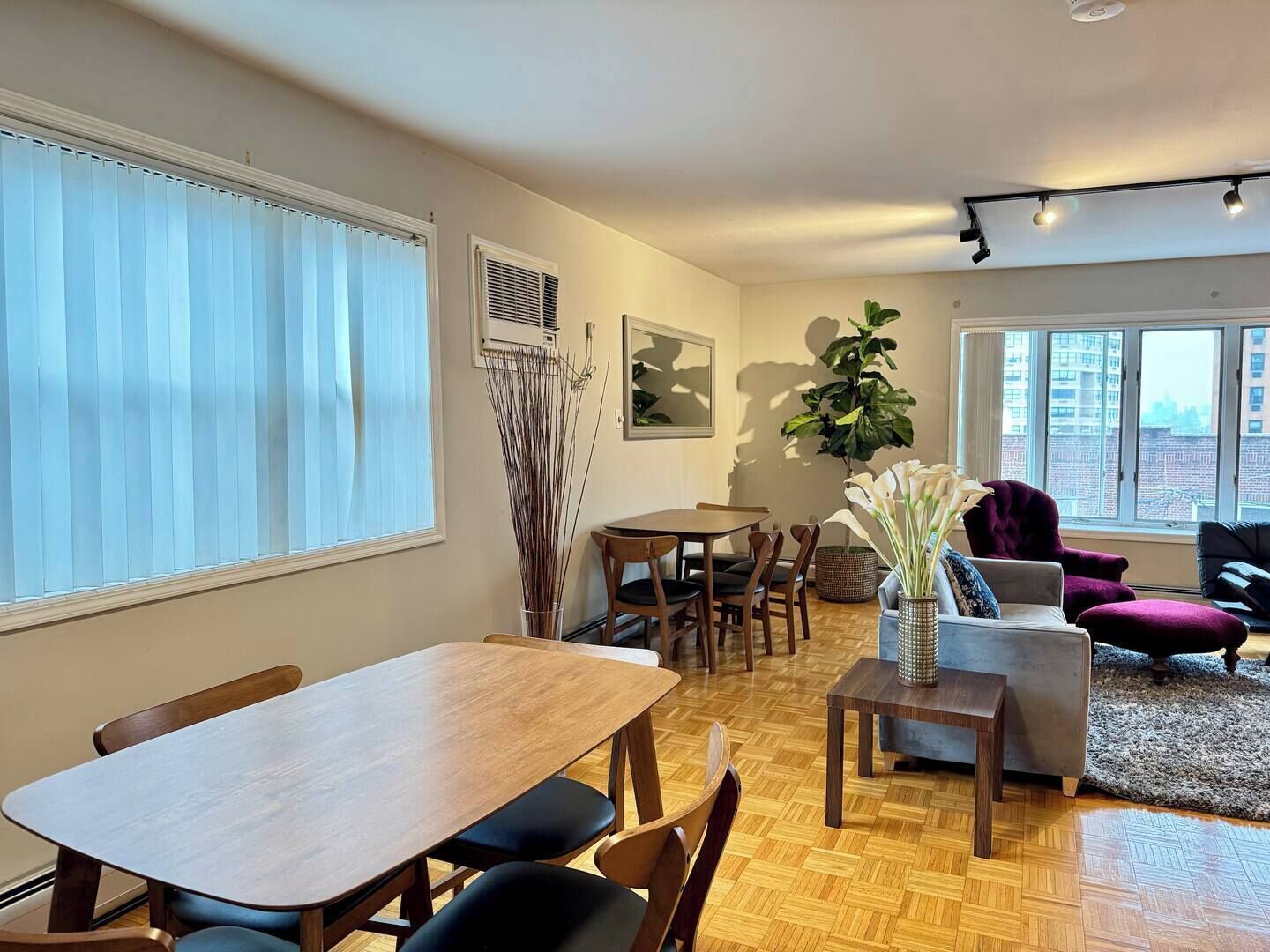 Ein modernes Wohnzimmer mit Essbereich, großen Fenstern und Blick auf die Stadt.