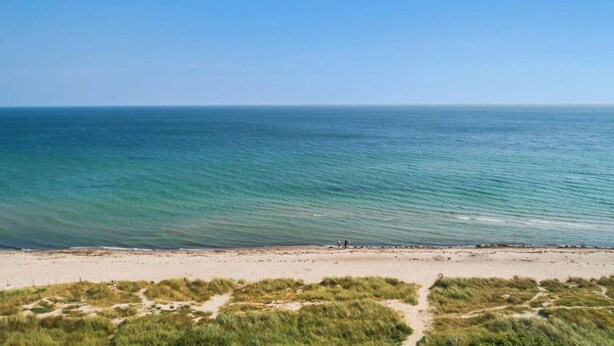 En strand med kristallklart blått vatten och en sandstrand.