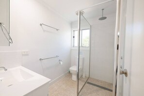 A bathroom with a white sink, toilet, and shower area.