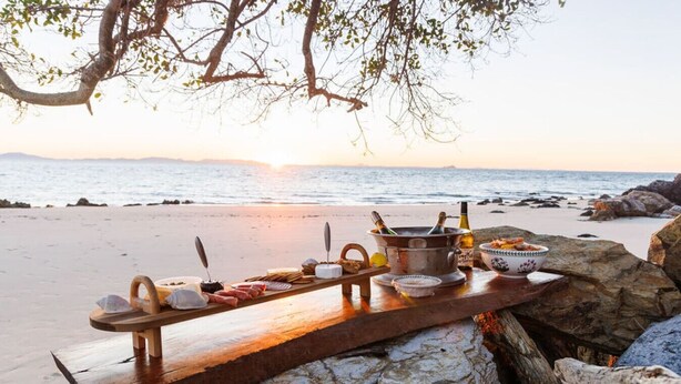 Un bar de fusta situat a una platja rocosa amb una vista al capvespre.
