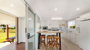 Una cocina moderna con una isla central, taburetes de bar y un puerta corrediza de vidrio que da a un área exterior.