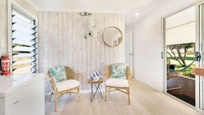 Una habitación moderna con dos sillas de mimbre, una mesita pequeña y un ventanal grande.
