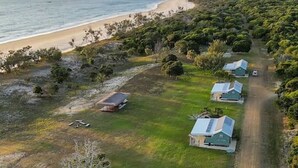 Vista aérea de una propiedad costera con un camino de tierra que conduce a una hilera de casas con paneles solares.