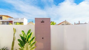 A modern outdoor area with a pink tiled wall, a concrete bench, and various plants including a large banana plant. - Stylish Private Pool Villa in Pererenan (Munggu)