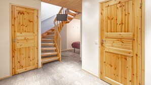 A hallway with wooden doors, a staircase, and a bed with a red cover.