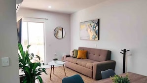 A living room with a sofa, a coffee table, and a dining table. - Apartment with an artificial beach! (Mazatlán)