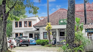 A residential area with a white building, parked cars, and lush greenery.