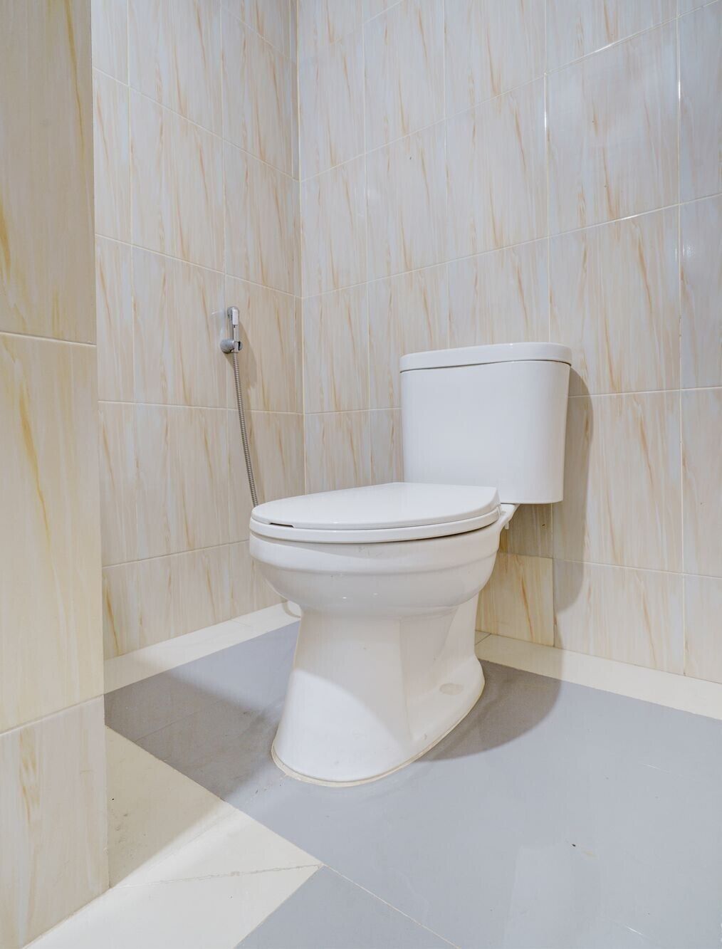 A white toilet in a bathroom with marble walls and a tiled floor.