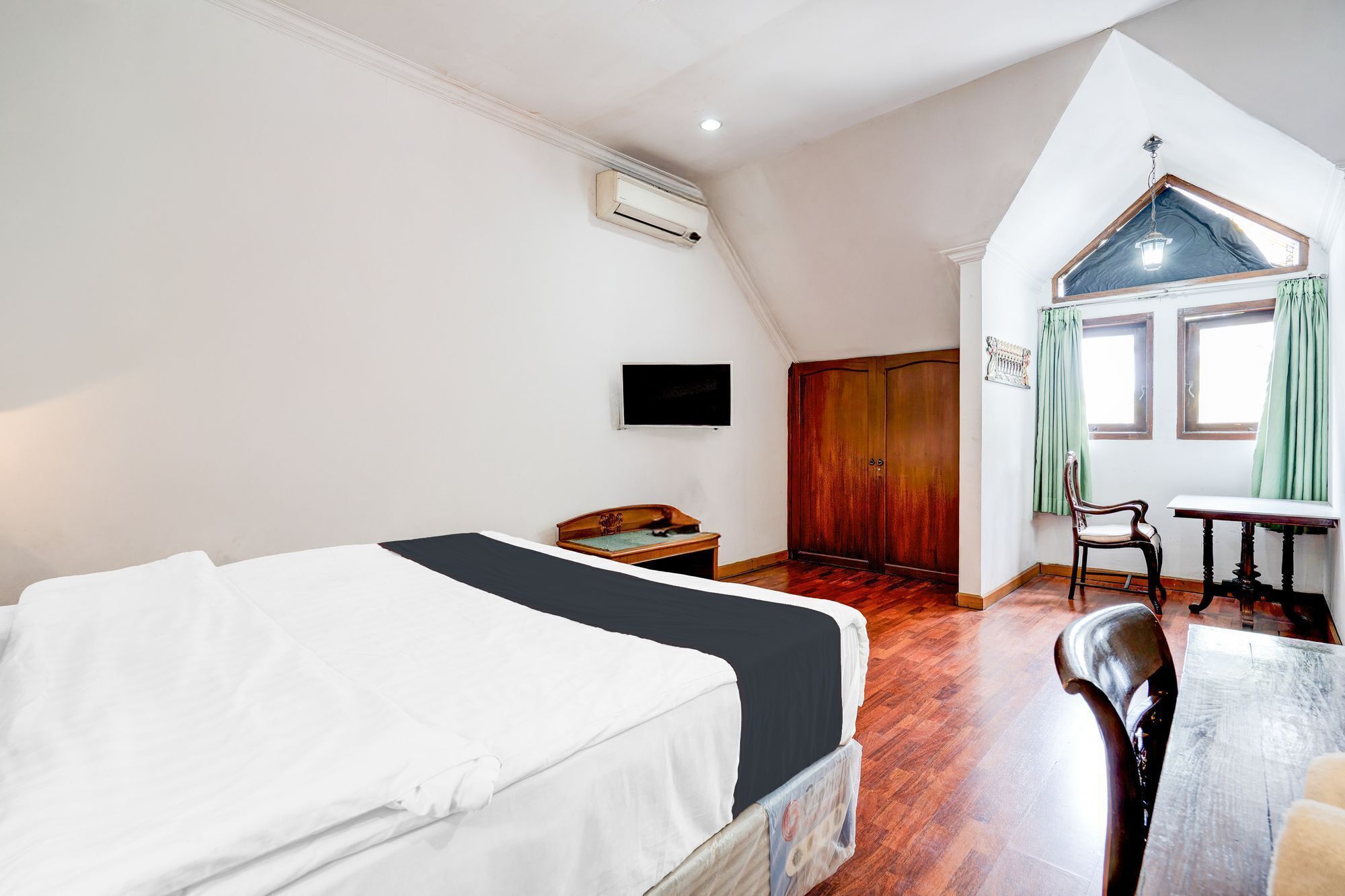 A bedroom with a bed, a desk, a chair, a TV, and a wardrobe.