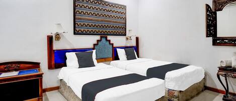 A double bed with a patterned headboard, a nightstand, a mirror, and a wall-mounted artwork.