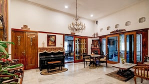 A spacious room with a piano, a chandelier, and a dining area with a table and chairs.