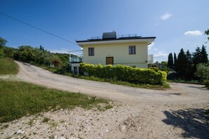 A two-story house with a dirt driveway leading to a gated entrance. - Domus Garda Relax (Garda)
