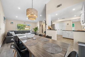 A modern dining area with a wooden table, black chairs, and a woven pendant light.