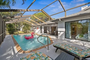 A pool area with a glass ceiling, lounge chairs, and a flamingo float. - Florida Fun! Beach Theme, Heated Pool, Near Siesta (Sarasota)