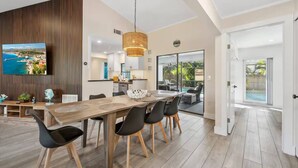 A spacious dining area with a long wooden table, black chairs, and a hanging light fixture. - Tropical Retreat – Gulf Gate Retreat w/ Heated Pool, 7 Beds, Near Siesta Key, Families/Couples Only (Sarasota)
