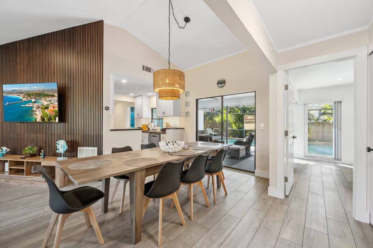 Un comedor moderno con una mesa de madera, sillas negras y una lámpara colgante.