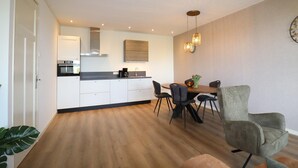 Une cuisine moderne avec des meubles blancs, un four encastré et un coin repas comprenant une table et des chaises.