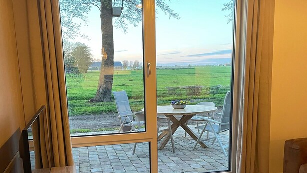 Une pièce dotée d’une porte-fenêtre coulissante donnant sur un espace extérieur aménagé avec une table et des chaises.