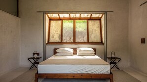 Une chambre à coucher avec un lit en bois, une grande fenêtre à cadre en bois et deux tables de chevet avec des lampes.