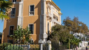 Un bâtiment historique à la façade jaune, doté de fenêtres en arc de cercle et d’une tour centrale.