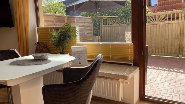 A modern kitchen with a white countertop, a built-in bench, and a window overlooking a garden. - The "Seebär" in Haus Meeresglück, close to the beach and central! - House Meeresglück (Dahme)