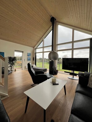 Un salón amplio con un gran ventanal, chimenea, televisor y sofá.