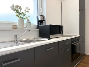 A modern kitchen with a built-in microwave, a coffee maker, and a sink.