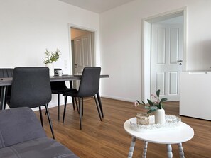 A modern living room with a sofa, dining table, chairs, and a coffee table with decorative items.