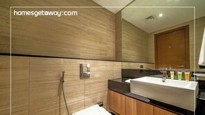 A modern bathroom with a large mirror, a sink with toiletries, and a shower. - Modern Studio Living at Missoni (Dubai)
