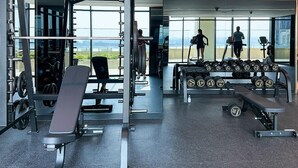 A modern gym with weightlifting equipment, treadmills, and dumbbells. - Modern Studio Living at Missoni (Dubai)